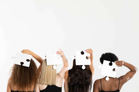 Different ethnicity and the same genes represented by matching puzzle pieces. Four women turned away.の写真素材