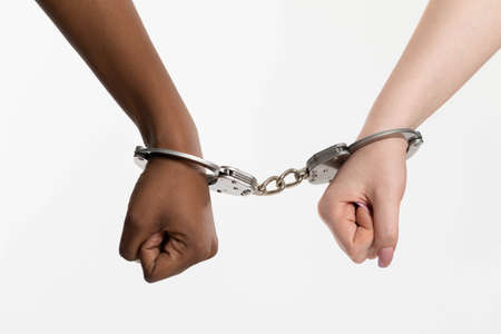 Handcuffs for two teenagers for petty crimes. African and European in shackles.の写真素材
