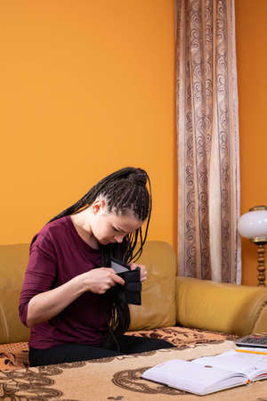 Empty wallet with money.rs were left with the last pennies of spending savings until the end of a long month. The girl holds a dime in her fingers, hoping for a better future.の写真素材