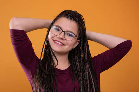 A relaxed young girl with a smile on her face. Hair arranged in small tiny braids. Put your hands...