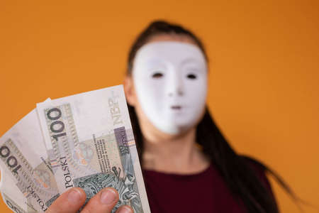 Paper notes held in a hand. A young adult holds up cash with her fingers. Hands stretched out in front of me. African braids.の写真素材