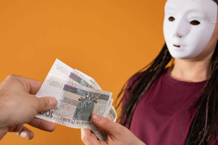 The male hand takes money from a stranger who has a mask all over his face so that no one will...