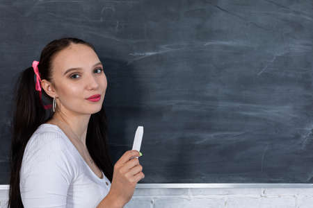 A teenager stands and looks straight into the lens. The girl has long dark hair tied with pink bows on both sides of her head.の写真素材