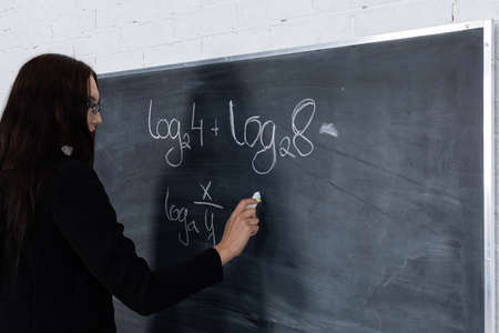 The teacher conducts a math lesson. A school board hung on a white brick wall. Class at school.の写真素材