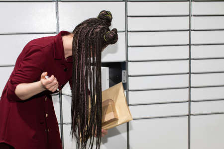 He carefully checks the opened mailbox. Young teenage girl with an interesting hairstyle. African braids.の写真素材