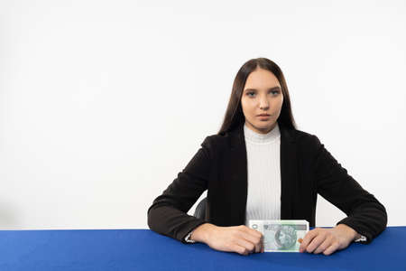 Young adult sitting at the table with money in hand. The ban employee is waiting for the customer...