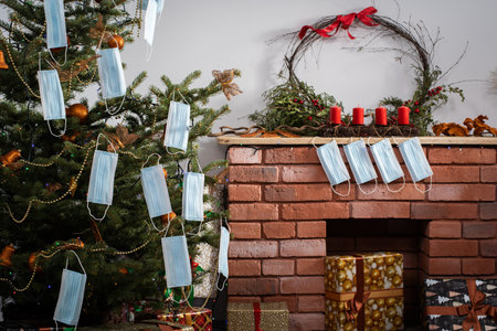 Gifts for the holidays lie under a decorated spruce tree in the large living room of the house. Family holidays despite the global COVID-19 viral disease.の写真素材