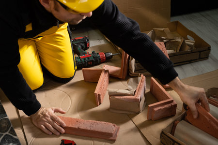 Every now and then a manual worker reaches for the next element of the decorative brick in order not to interrupt the planned work. A manual worker dressed in all personal protective equipment.の写真素材
