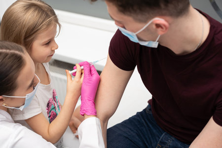 For fun, the nurse shows the girl how to administer the injections. The child performs the vaccine...