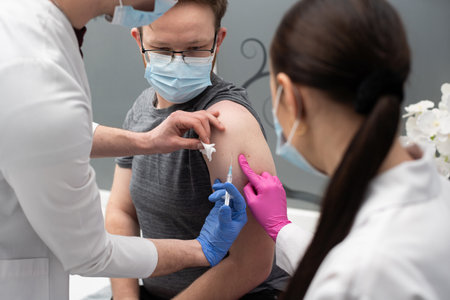 A young medical apprentice learns to administer injections under the supervision of an experienced nurse. An injection with a new vaccine formulation against COVID19 and other infectious diseases.の写真素材