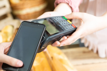 The client pays for the purchased bread through the payment terminal using a mobile phone. Cashless...