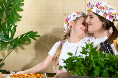 While eating a meal in the home kitchen, the daughter hugs her beloved mother. The love and joy of mom and daughters moments together in the home kitchen.の写真素材
