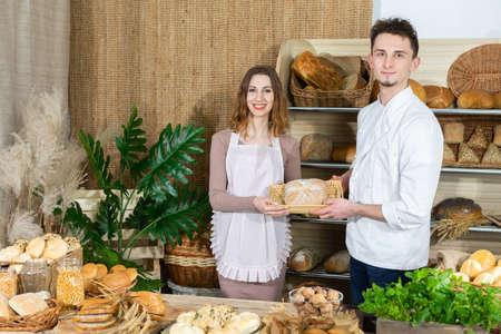 At the bakery stand, a saleswoman and a baker advertise their latest idea for a cracked loaf of...