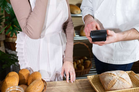 During a short training at the start of a new job in operating a payment machine. A multi-generation baking tradition.の写真素材