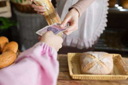 The customer pays for the purchased bread in cash directly to the sellers hand. A multi-generation...