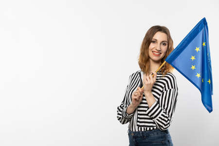 A smiling girl holds in her hand one flag of the European Union. Isolated from the background.
