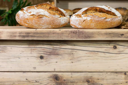 In a bakery shop, on an old wooden counter, there are two well-baked loaves of bread in wheat flour...