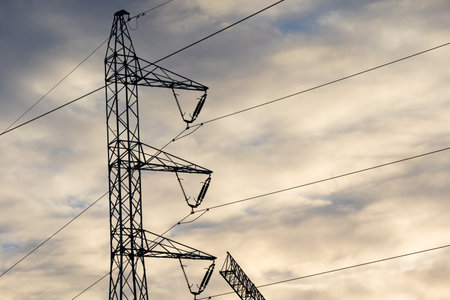 A power pole built on the basis of a truss against the sky and clouds at sunset.