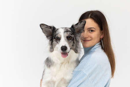 Happy teenage girl holds her dog in her arms. Border Collie dog. A purebred dog with a proven...