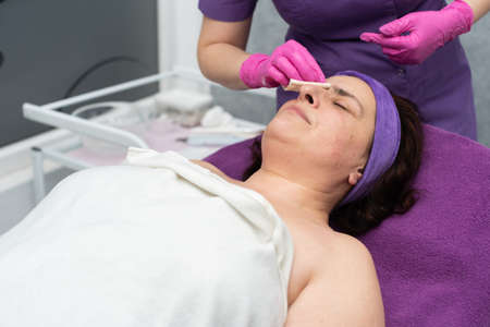 After washing the face with the gel, the beautician wipes dry the remains of the wet gel from the...