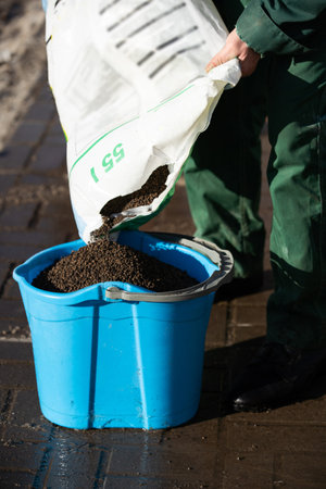 Up close you can see how an employee is pouring expanded clay from the bag into a bucket, which he...