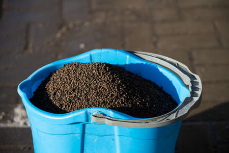 A blue bucket filled to the brim with expanded clay necessary for sprinkling slippery pavementsの写真素材
