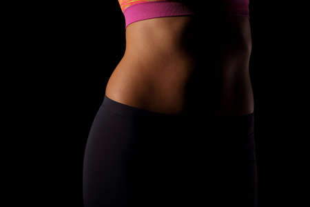 The female belly is perfectly muscled and trained and the whole set is placed on a black backgroundの写真素材