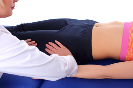 The physiotherapist performs a relaxing massage of the hip muscles by gently rocking them from side to sideの写真素材