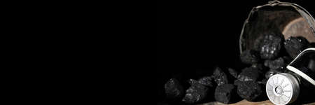 A gas mask lies on a wooden platform against a background of black coal. Panoramic frame