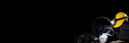 On black coal folded mining accessories: yellow helmet with flashlight, dust mask with filter. Panoramaの写真素材