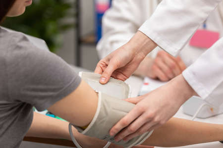 Close-up view of a nurse placing a blood pressure monitor on a patients arm. General practitioner....