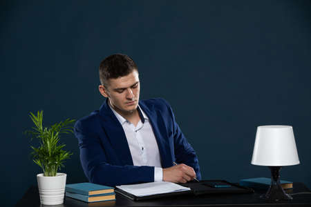 A young businessman reads a contract he is about to sign with a large financial consortium.の写真素材