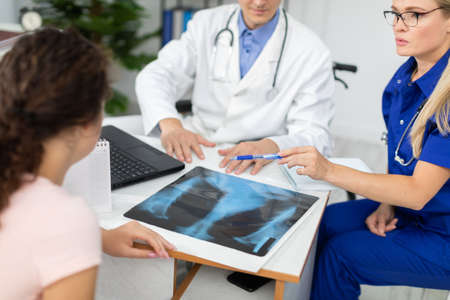 A doctor and a lady doctor are discussing an x-ray of their patients lungs.の写真素材