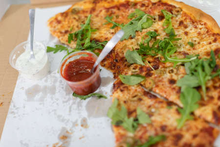 Unfinished pizza with arugula leaves at a college party.の写真素材