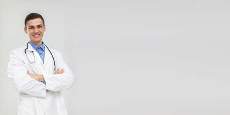 Smiling doctor stands forward with hands folded with a gentle smile. Panoramic view.の写真素材