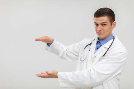 The doctor stands forward with a subdued expression and his hands raised.の写真素材
