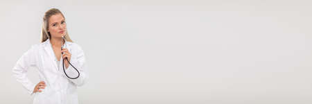 The doctor looks resolutely into the camera and holds a stethoscope in her hand. Panoramic frame.の写真素材