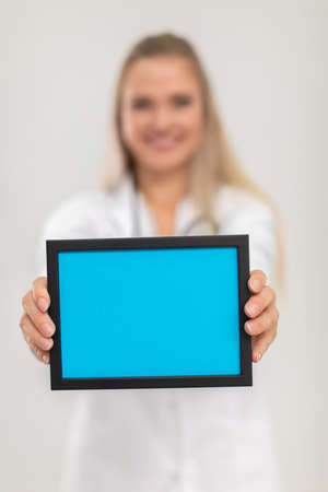 In the foreground is a rectangular blue plaque and in the background you can see a lady doctor.の写真素材