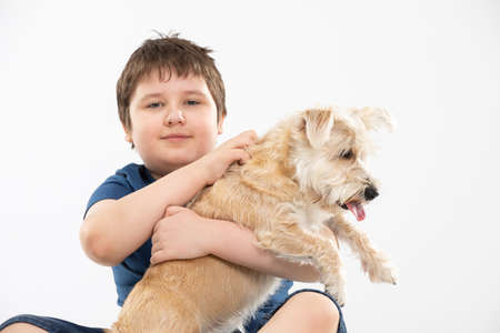 Young boy holds his dog in his arms and strokes it. Subject isolated from the background.の写真素材