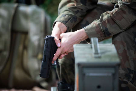The lady soldier sits on a chair and holds a gun in her hands.