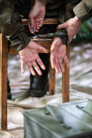 A guard unlocks the handcuffs of an accused soldier with a small key.