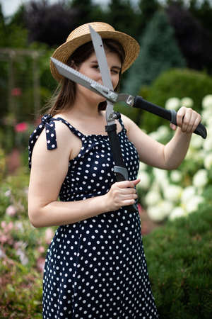 A young lady gardener shows off a large garden shears.
