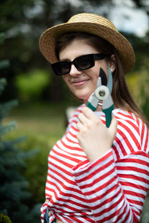 A young lady gardener demonstrates a garden secateurs.の写真素材