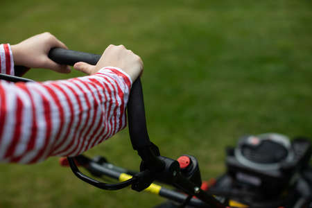 Close-up view of a girl holding a garden mower handle in her hands.の写真素材