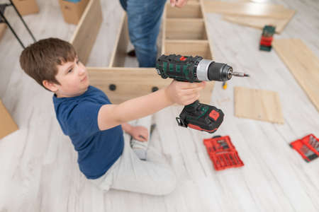 A young boy holds a cordless screwdriver in front of him.の写真素材