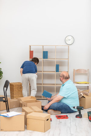 Dad and son arrange books on a bookcase immediately after moving.の写真素材