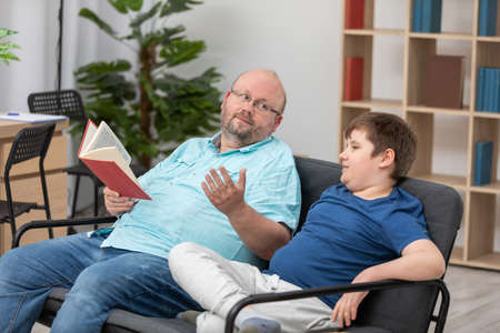 A father explains to his son what he has read in a book. Learning together.の写真素材