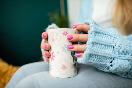 A womans hands wrap around a mug of hot drink.の写真素材