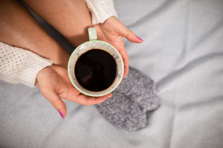 A cup of coffee held in a womans hands. Neat legs.の写真素材