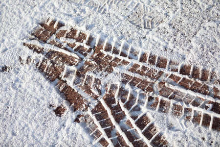 Fresh tire marks on soft snow on a city sidewalk.の写真素材